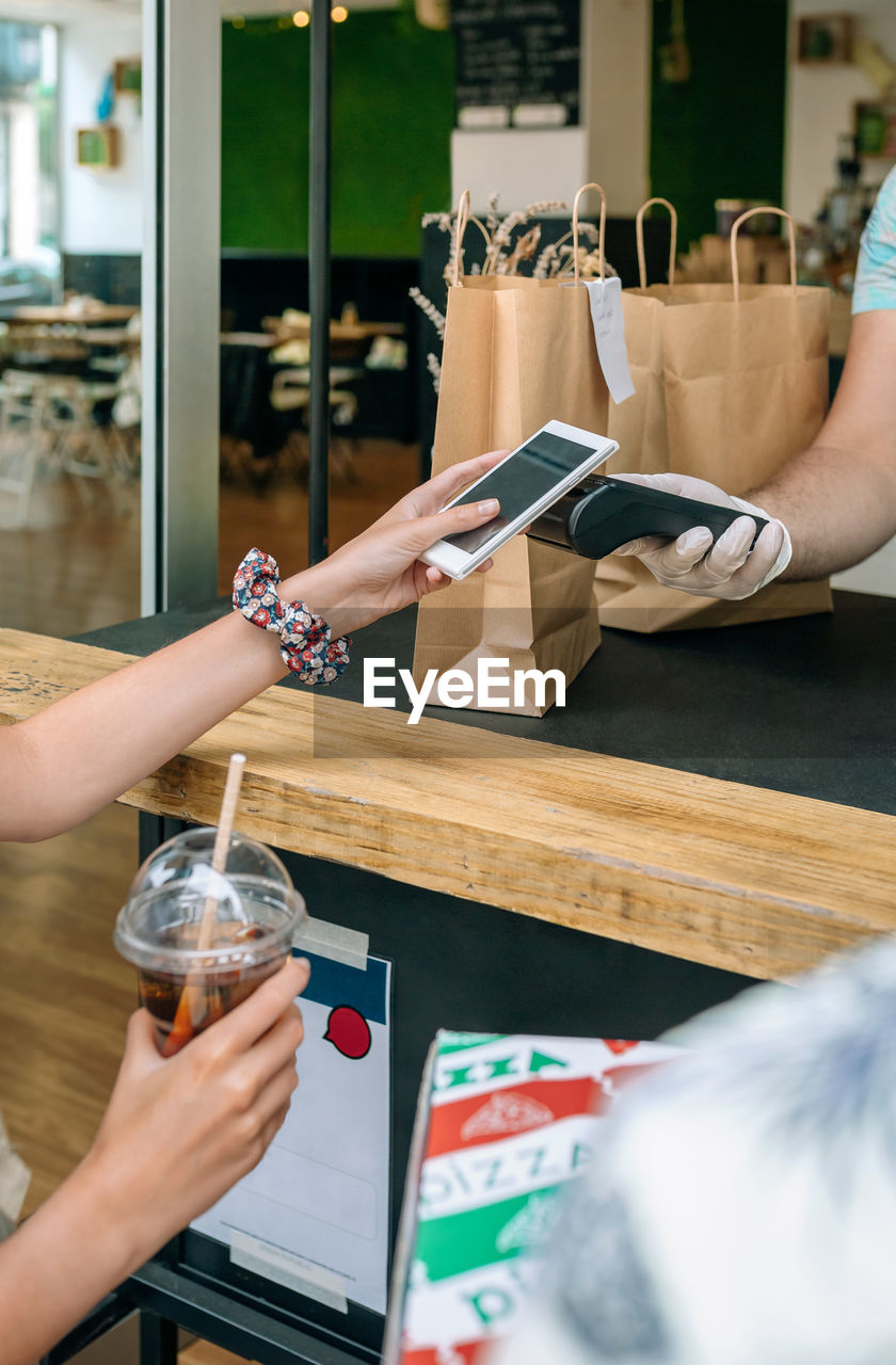 Woman making contactless payment through smart phone at restaurant