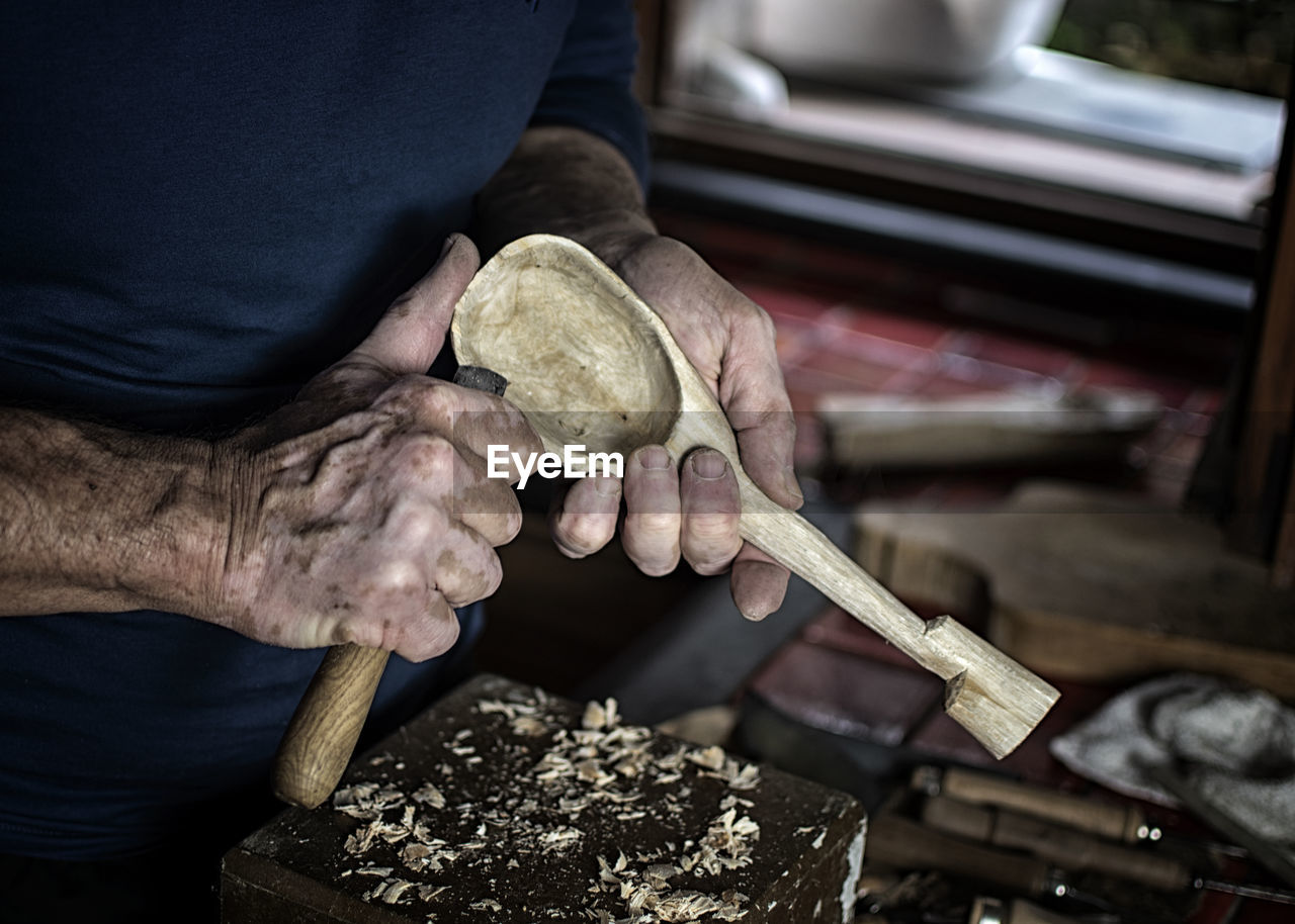Hands of craftsman who works wood and builds spoons with avocado wood