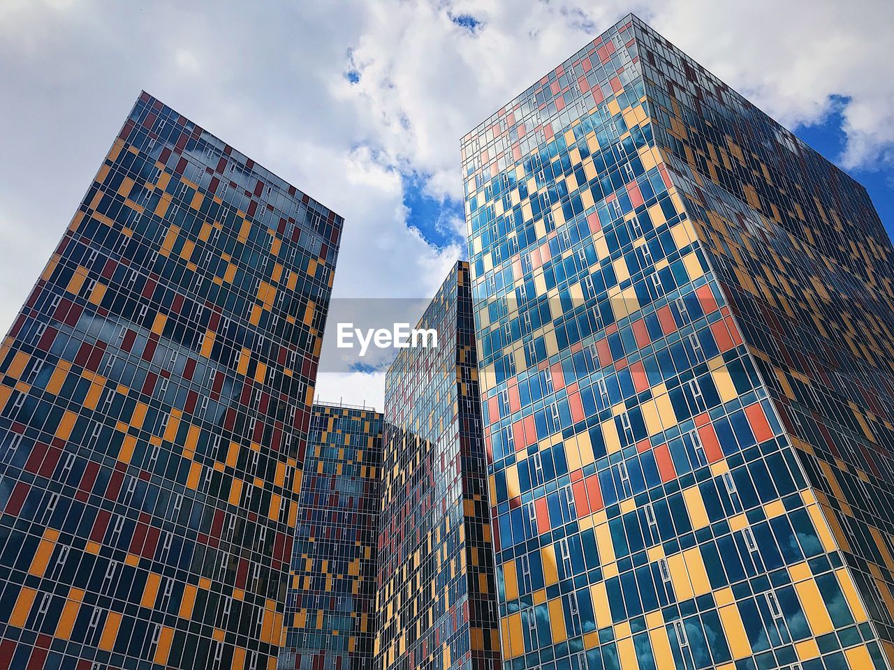 LOW ANGLE VIEW OF MODERN BUILDINGS AGAINST CLOUDY SKY