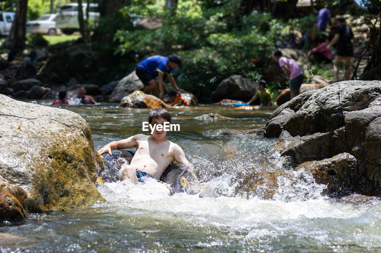 Portrait of shirtless man sitting in river