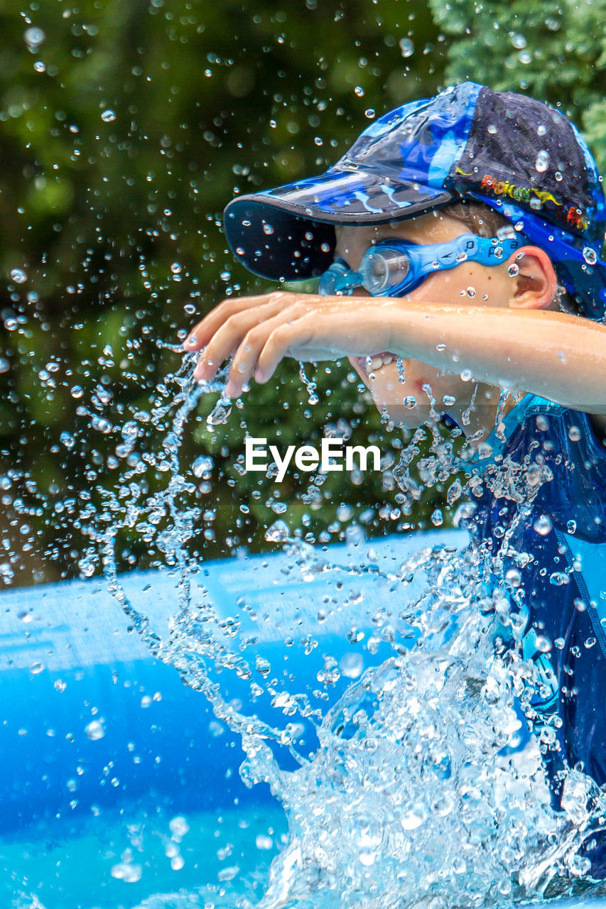 Side view of playful boy splashing water in wading pool