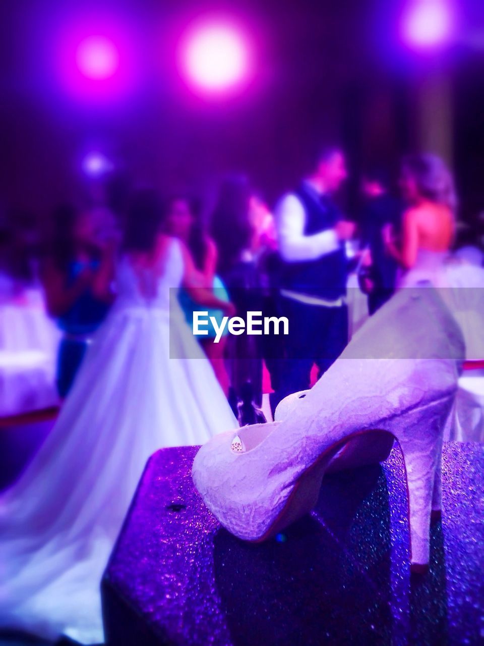 Close-up of high heels with people in background at wedding ceremony