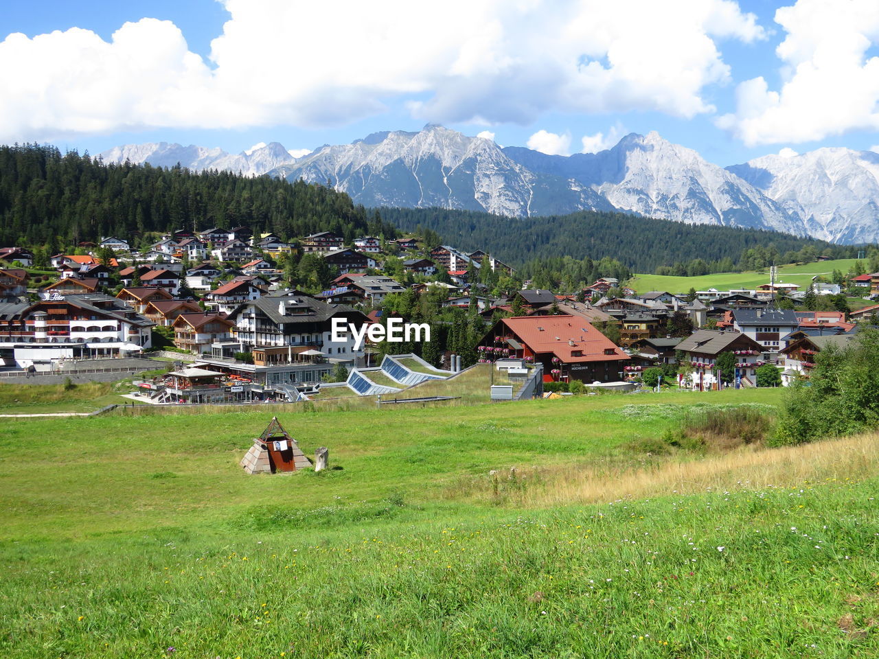 Village field by mountains against sky