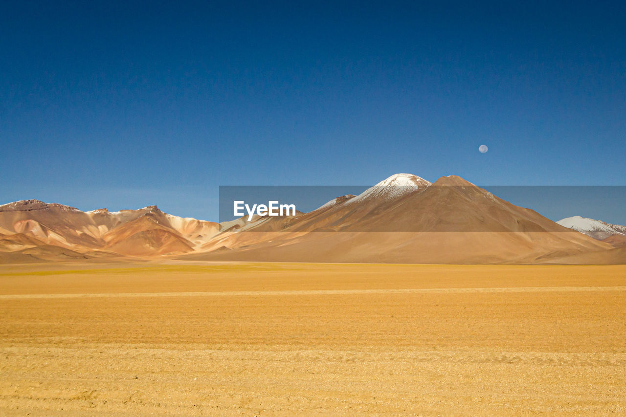 Scenic view of desert against clear blue sky