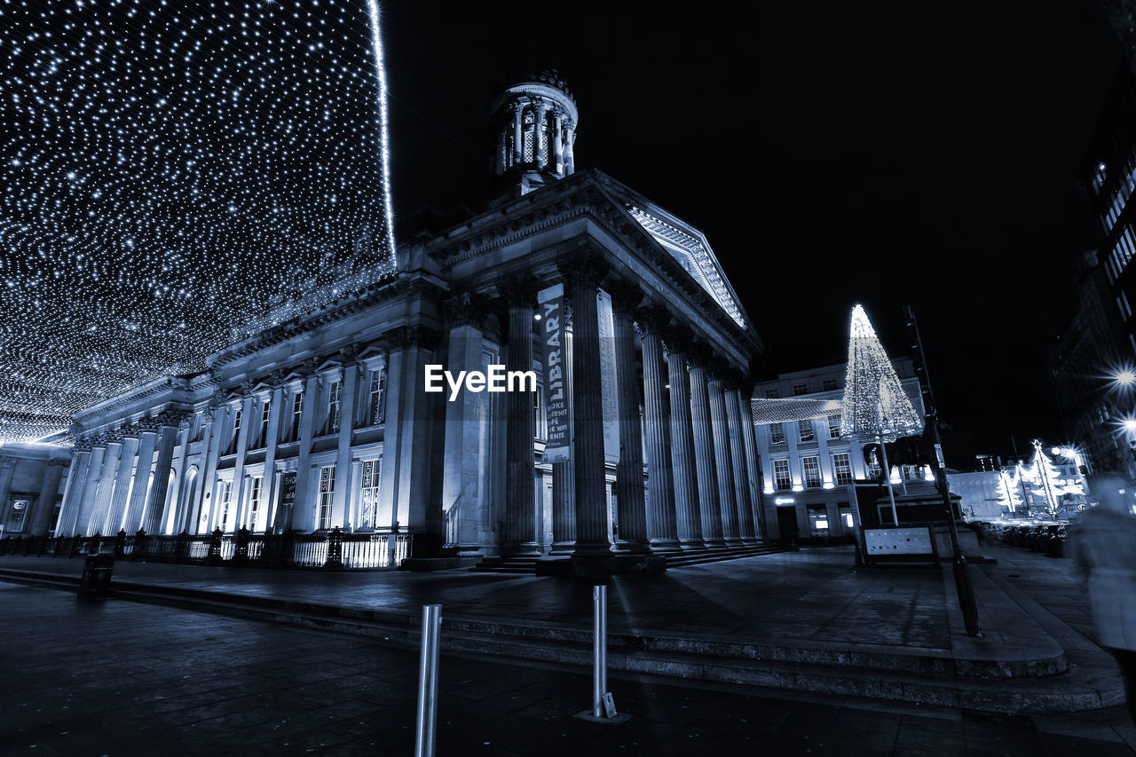 LOW ANGLE VIEW OF ILLUMINATED BUILDINGS AT NIGHT