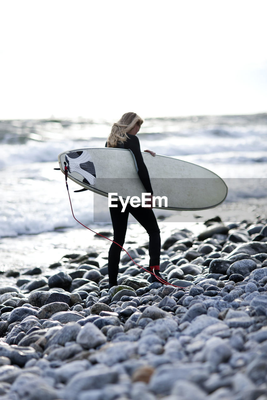 Woman with surfboard on beach