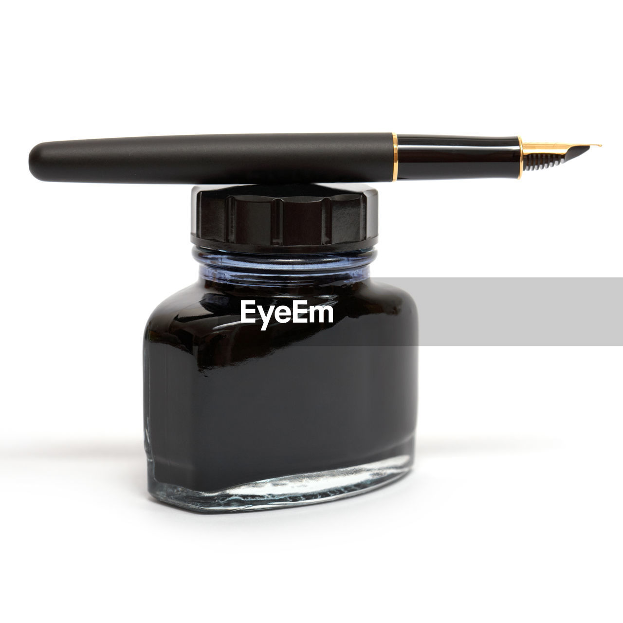 Close-up of pen and ink bottle on white background