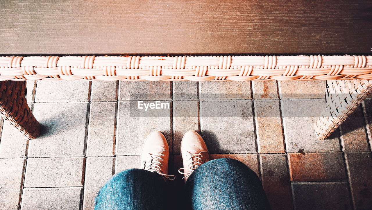 LOW SECTION OF WOMAN STANDING ON FOOTPATH BY TEXT ON FLOOR