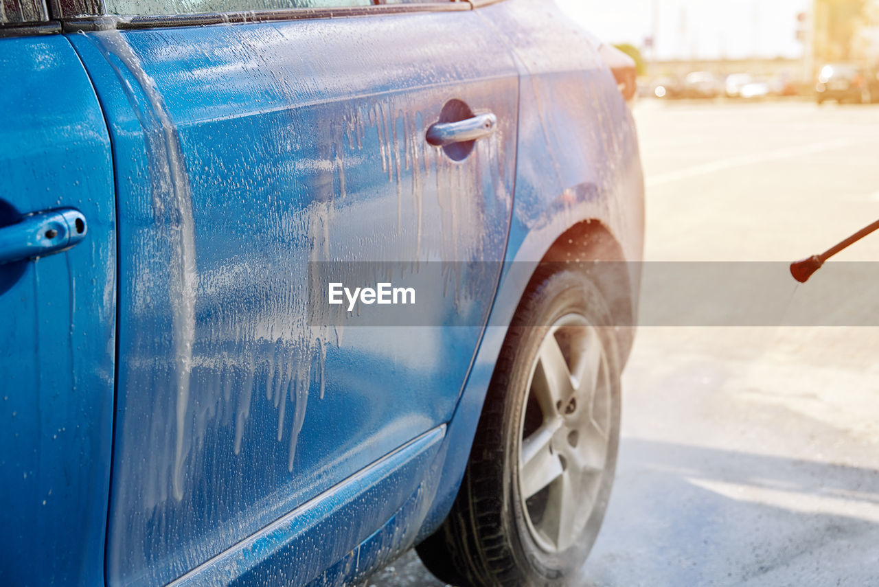 Cleaning car with high pressure water at car wash station