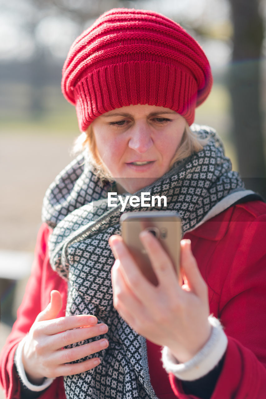 Young woman wearing warm clothing holding mobile phone