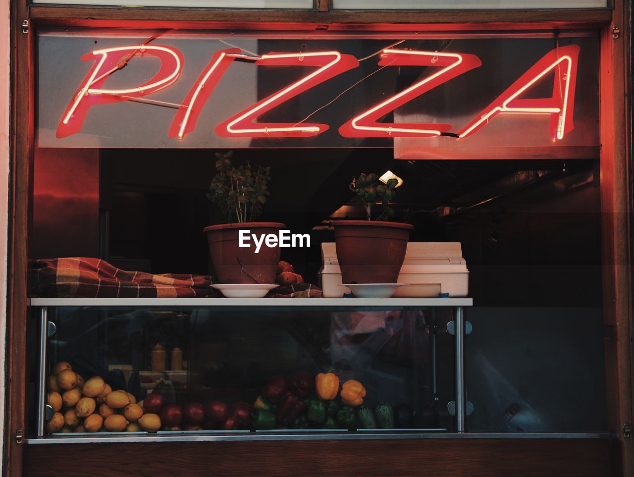 Illuminated pizza sign on glass