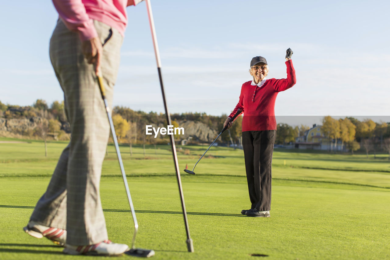 Full length of successful female golfer with friend on golf course