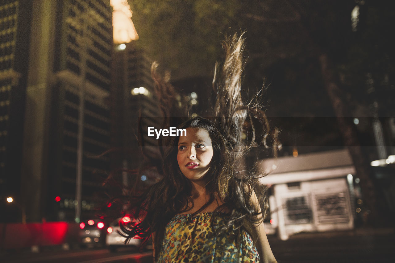 Portrait of woman standing in illuminated city at night