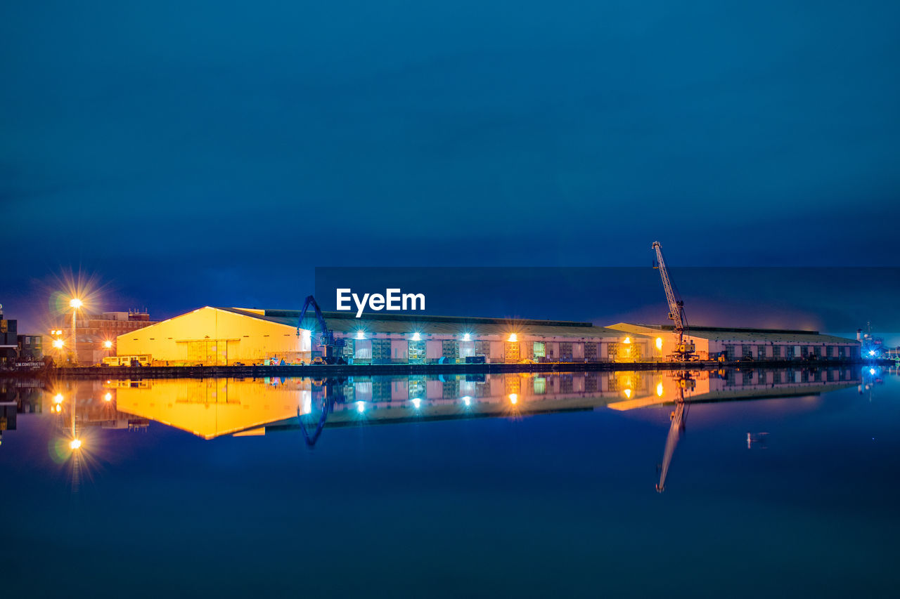 Illuminated built structure by sea against sky at night