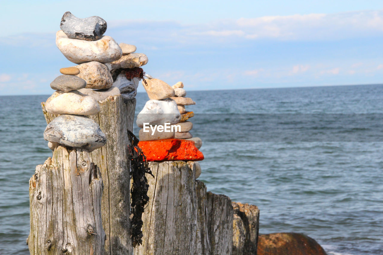 WOODEN POST IN SEA AGAINST SKY