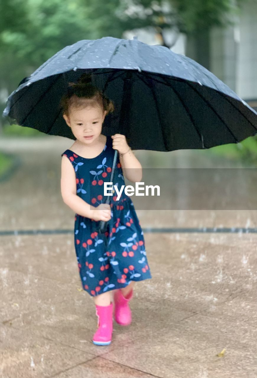 Portrait of young  girl with umbrella walking in the rain 
