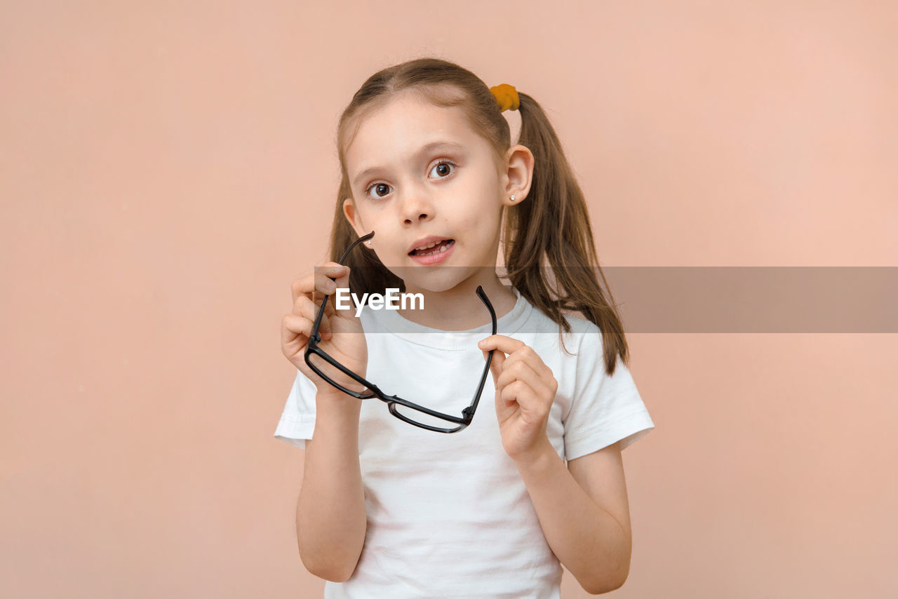 portrait of smiling young woman with stethoscope against pink background