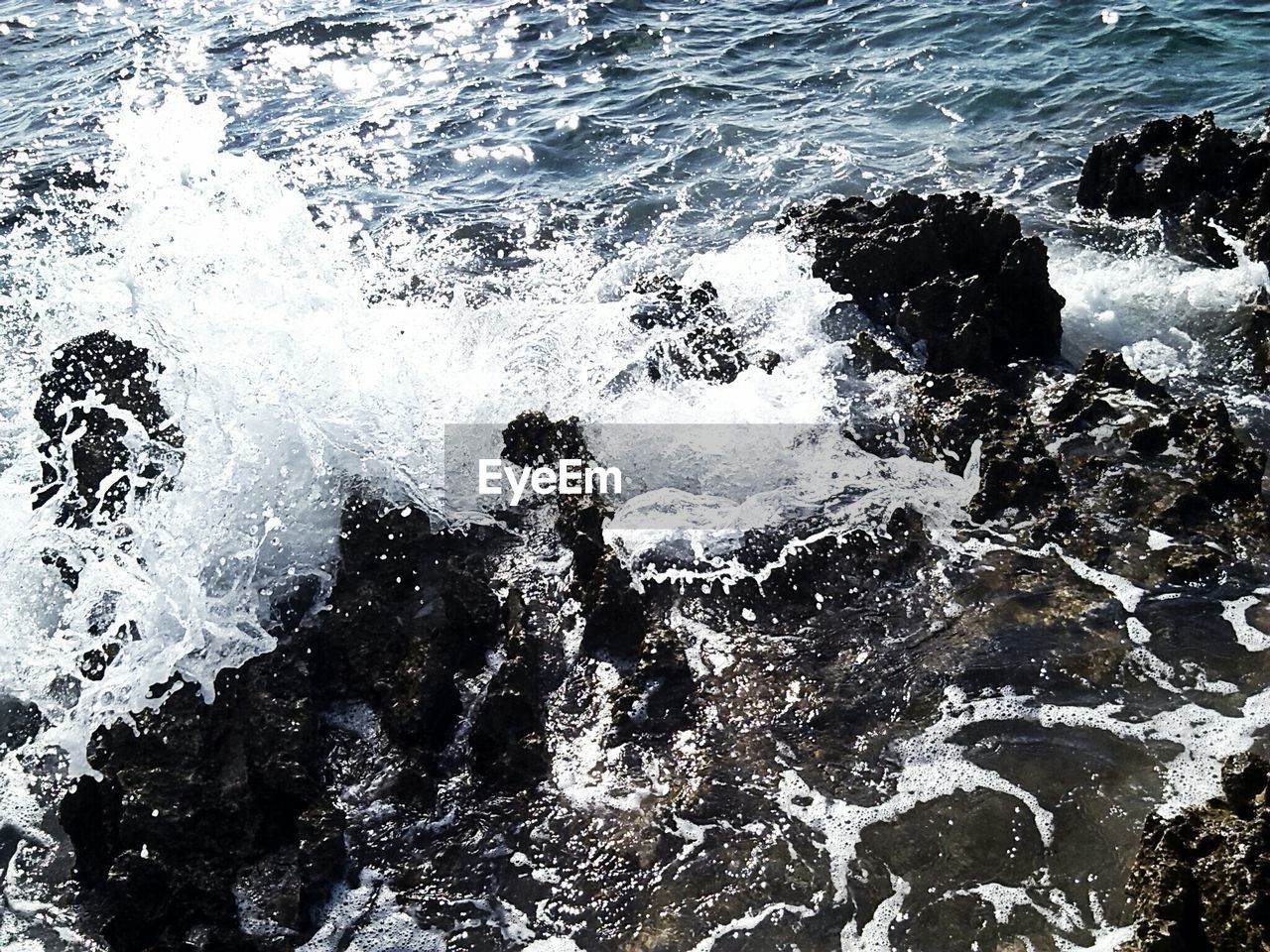 High angle view of wave splashing on rocks