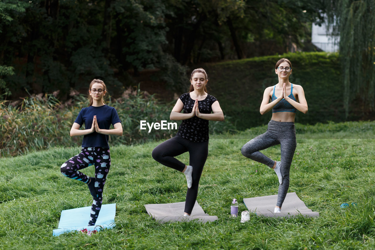 The relaxed girl is doing yoga in the park on carpet