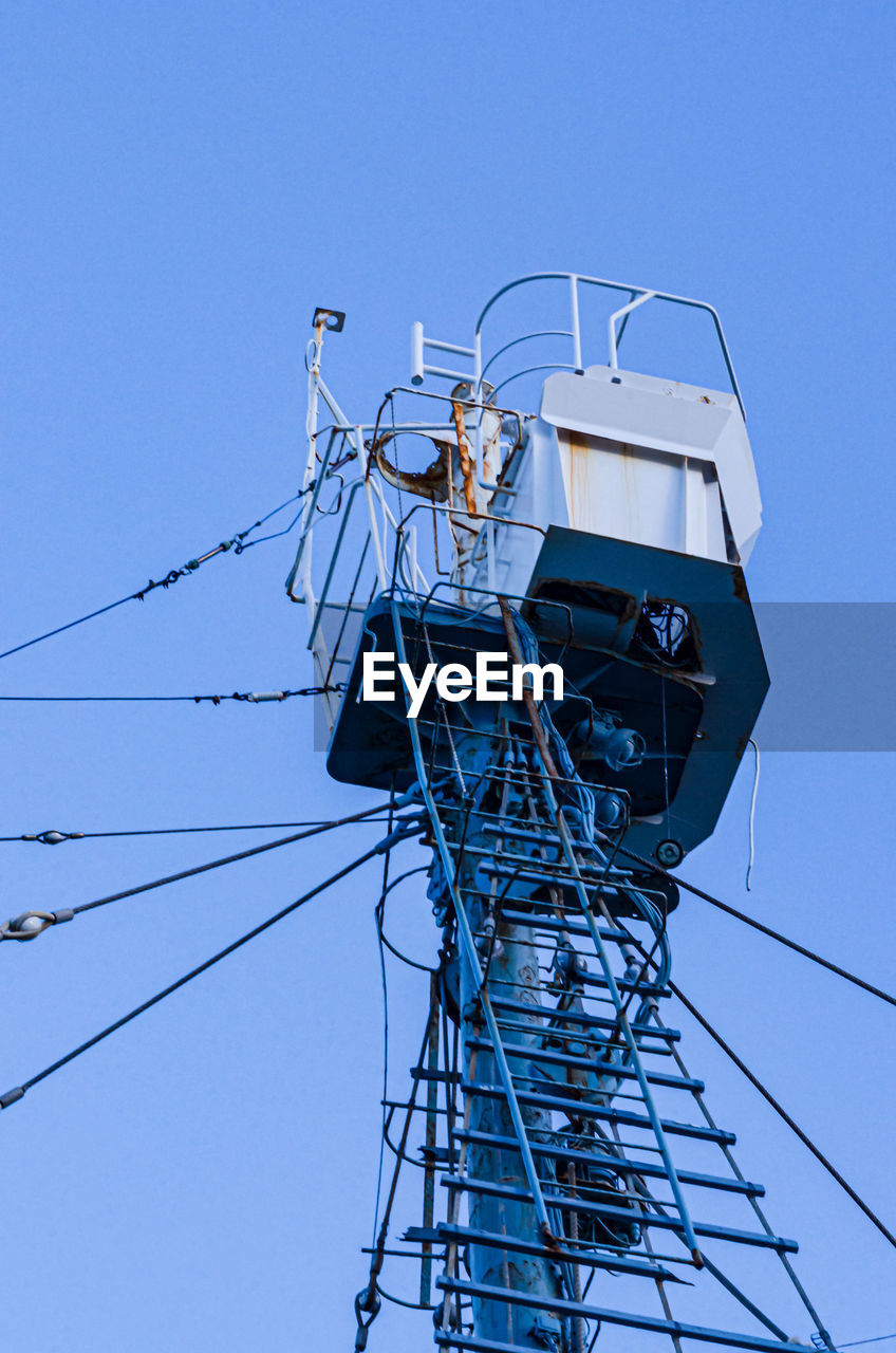 Low angle view of electricity pylon against clear blue sky