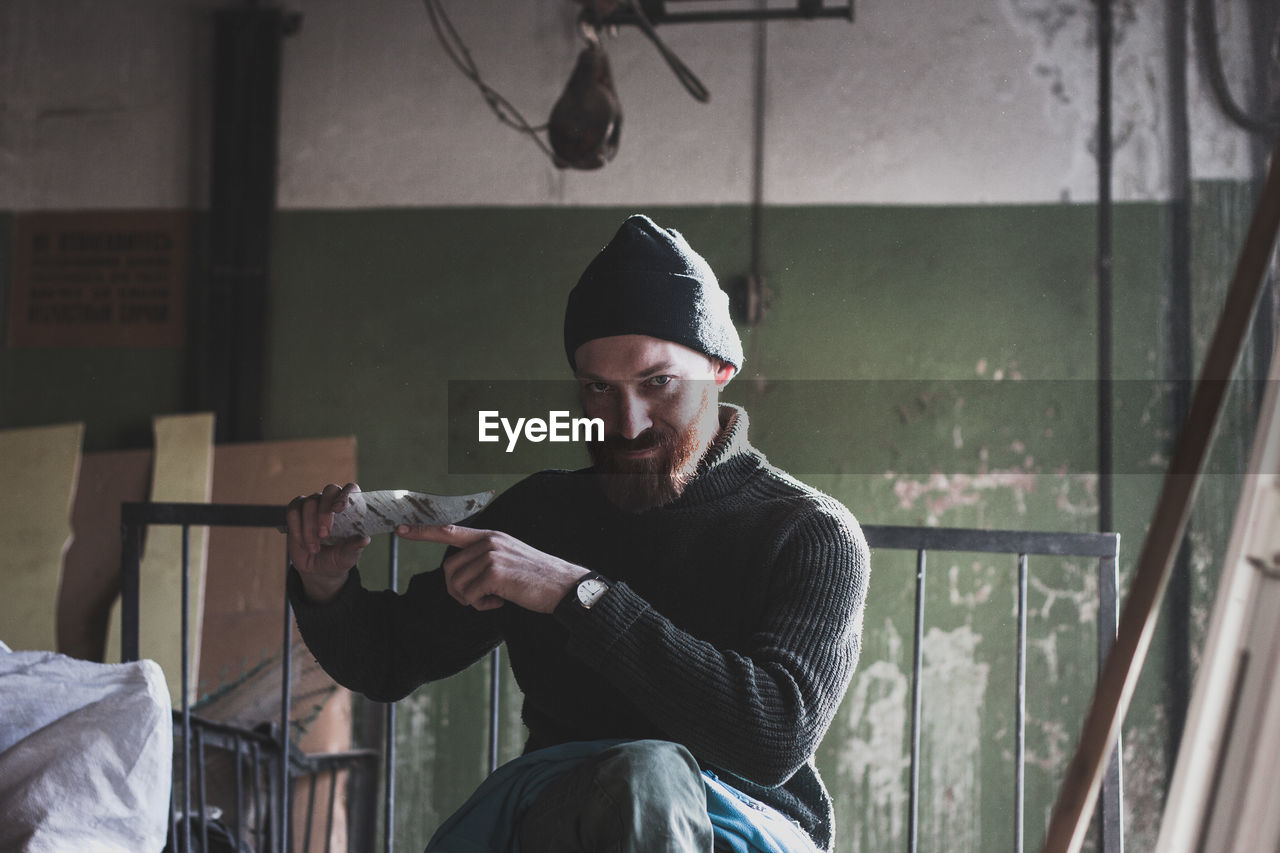 Portrait of young man holding broken glass at abandoned house