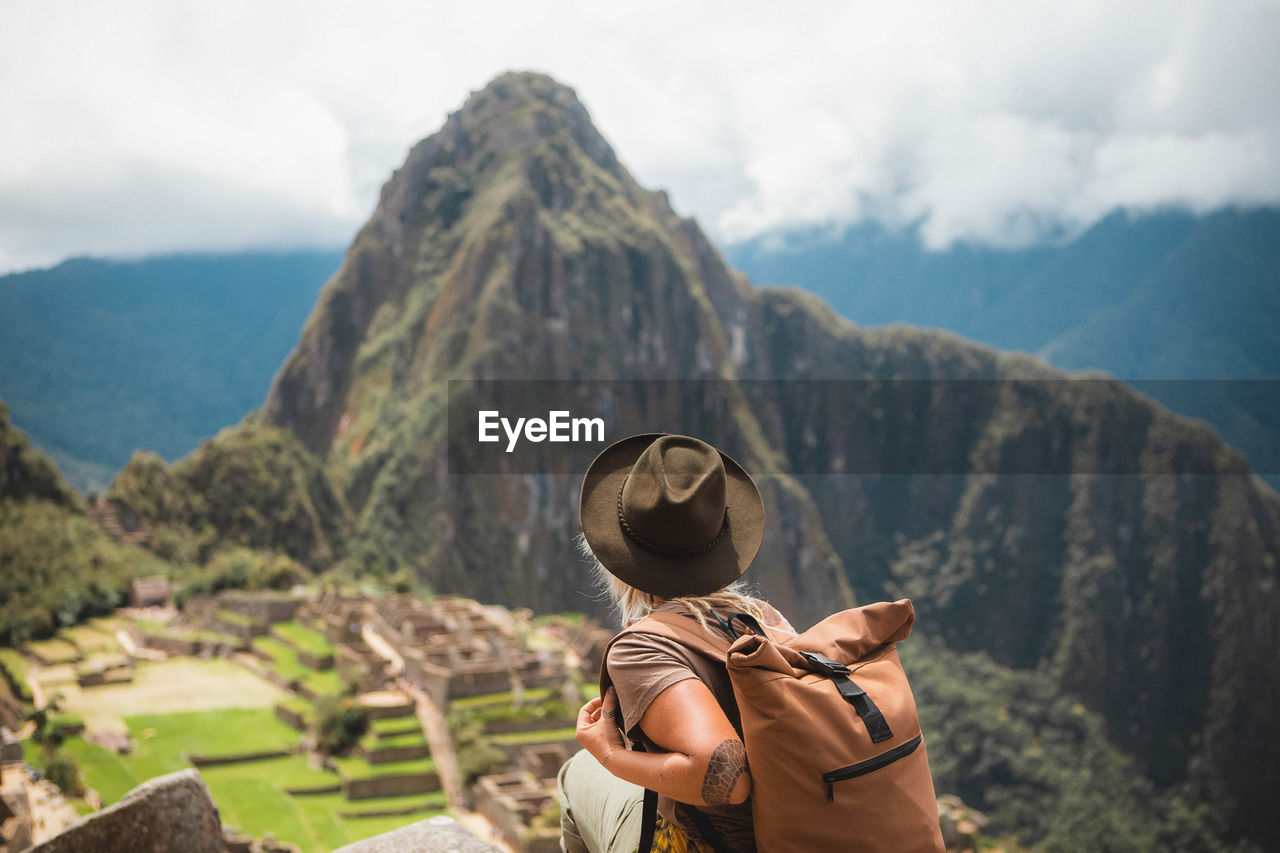 Rear view of woman looking at mountains against sky