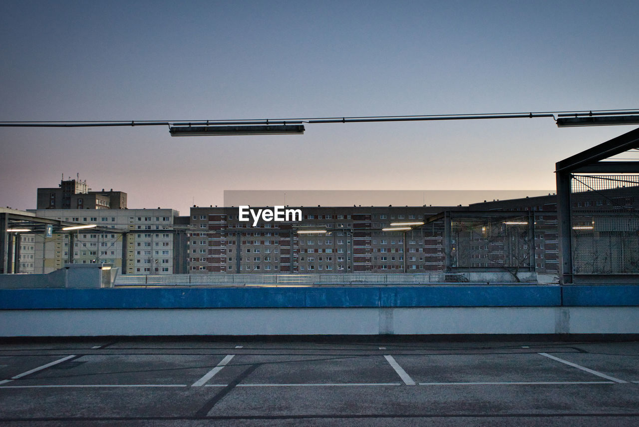 Empty road against buildings in city at sunset