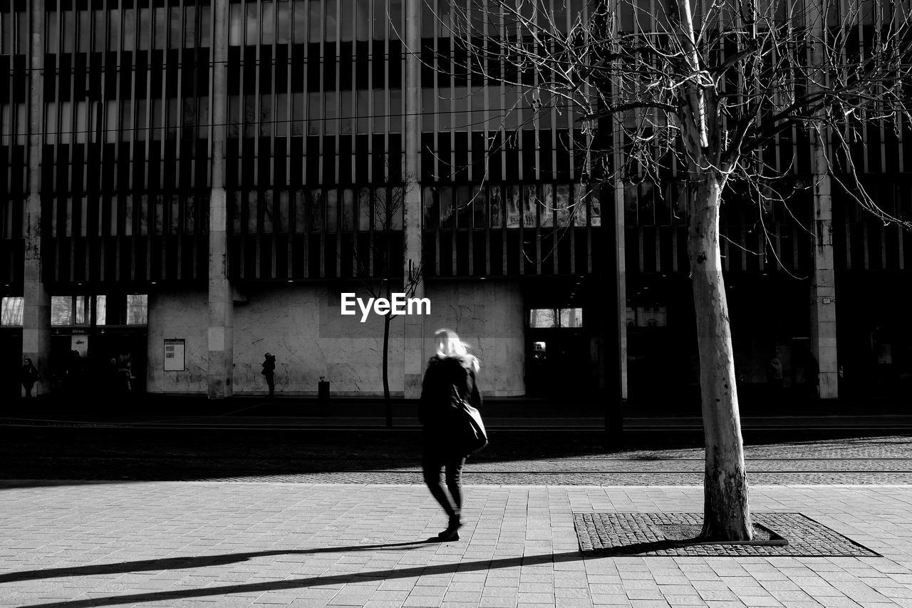 Woman walking on street against building in city