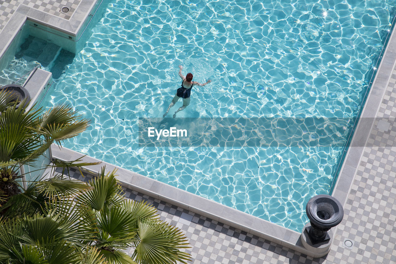 HIGH ANGLE VIEW OF WOMAN IN SWIMMING POOL