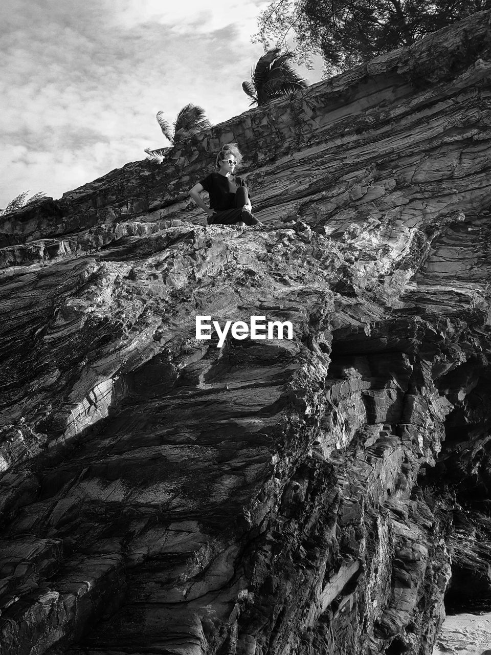 Low angle view of woman sitting on cliff