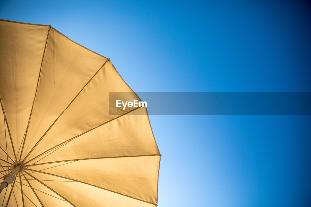 Low angle view of umbrella against clear blue sky