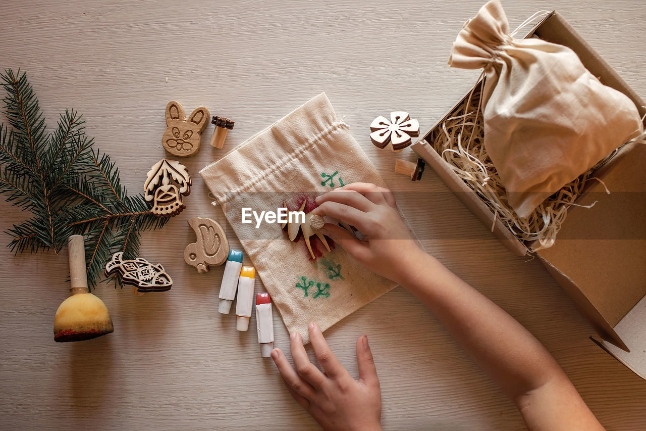 Girl doing craft wrapping for festive gifts with wooden stamp printing technique