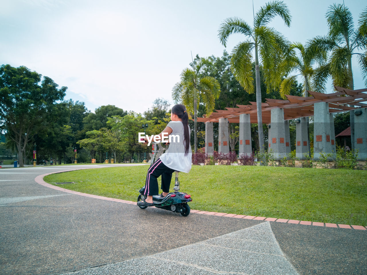 Full length of girl sitting on electric push motor on road against sky