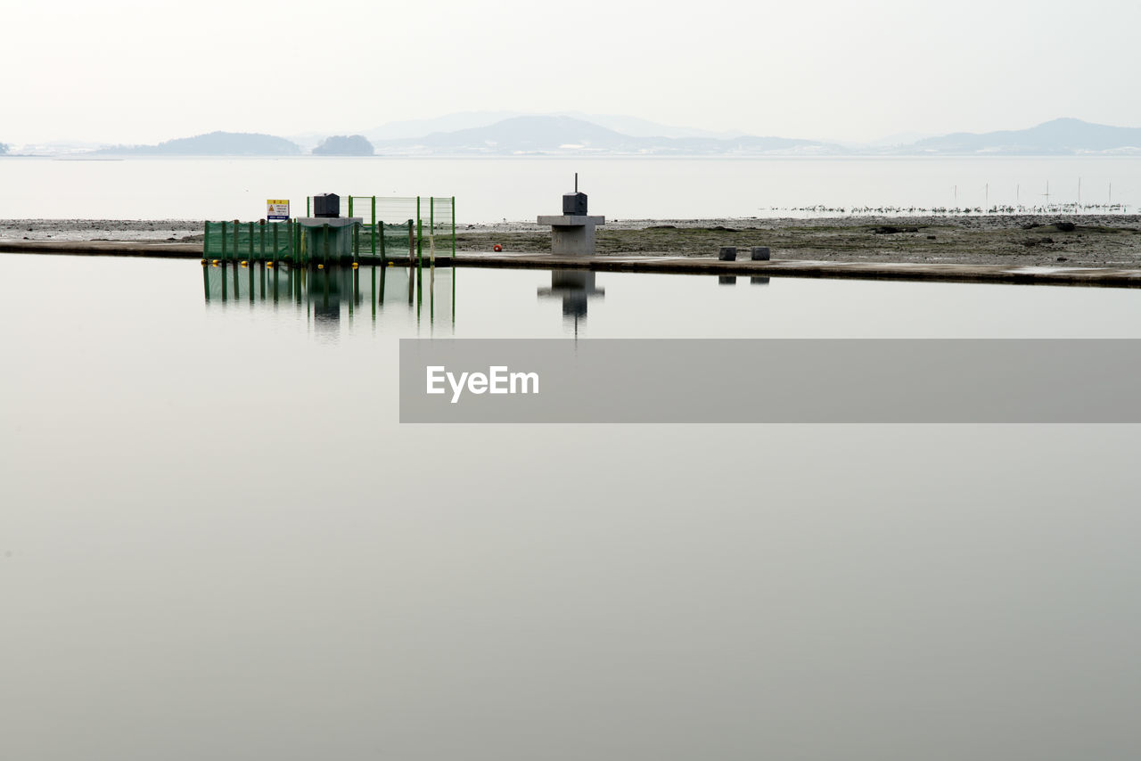 SCENIC VIEW OF WOODEN POSTS IN LAKE AGAINST SKY