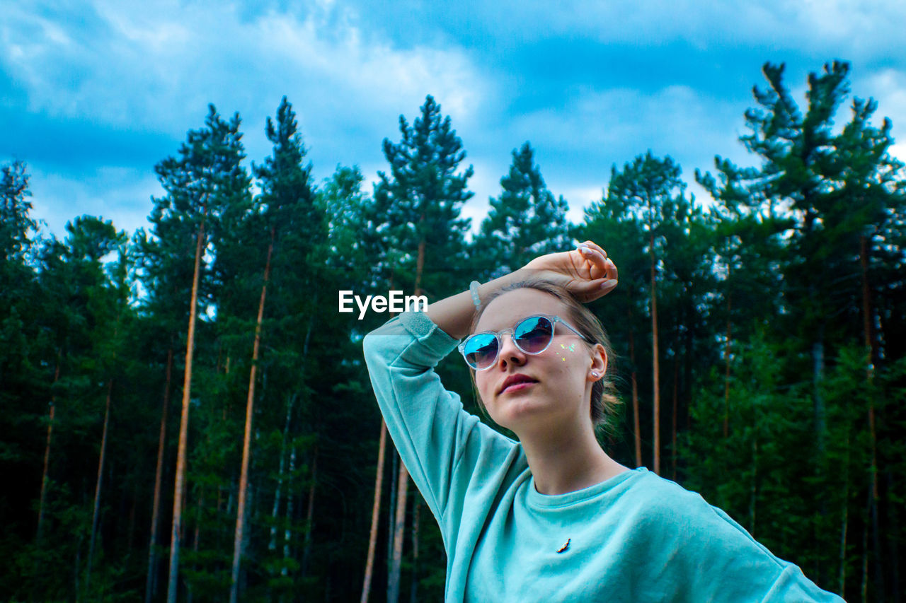 Portrait of smiling woman wearing sunglasses against trees