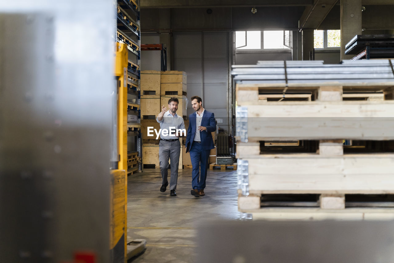 Businessman and colleague inspecting warehouse while walking at factory