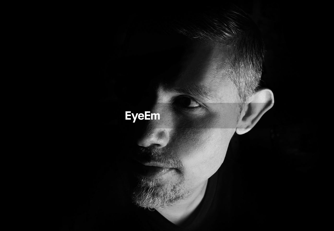 Close-up portrait of young man against black background