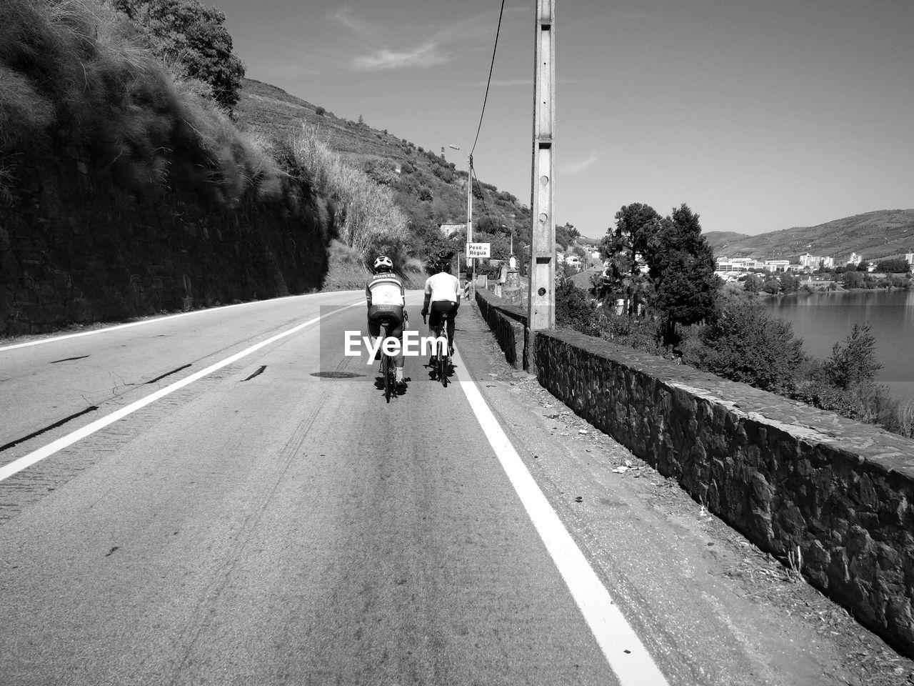 REAR VIEW OF MAN RIDING VEHICLES ON ROAD