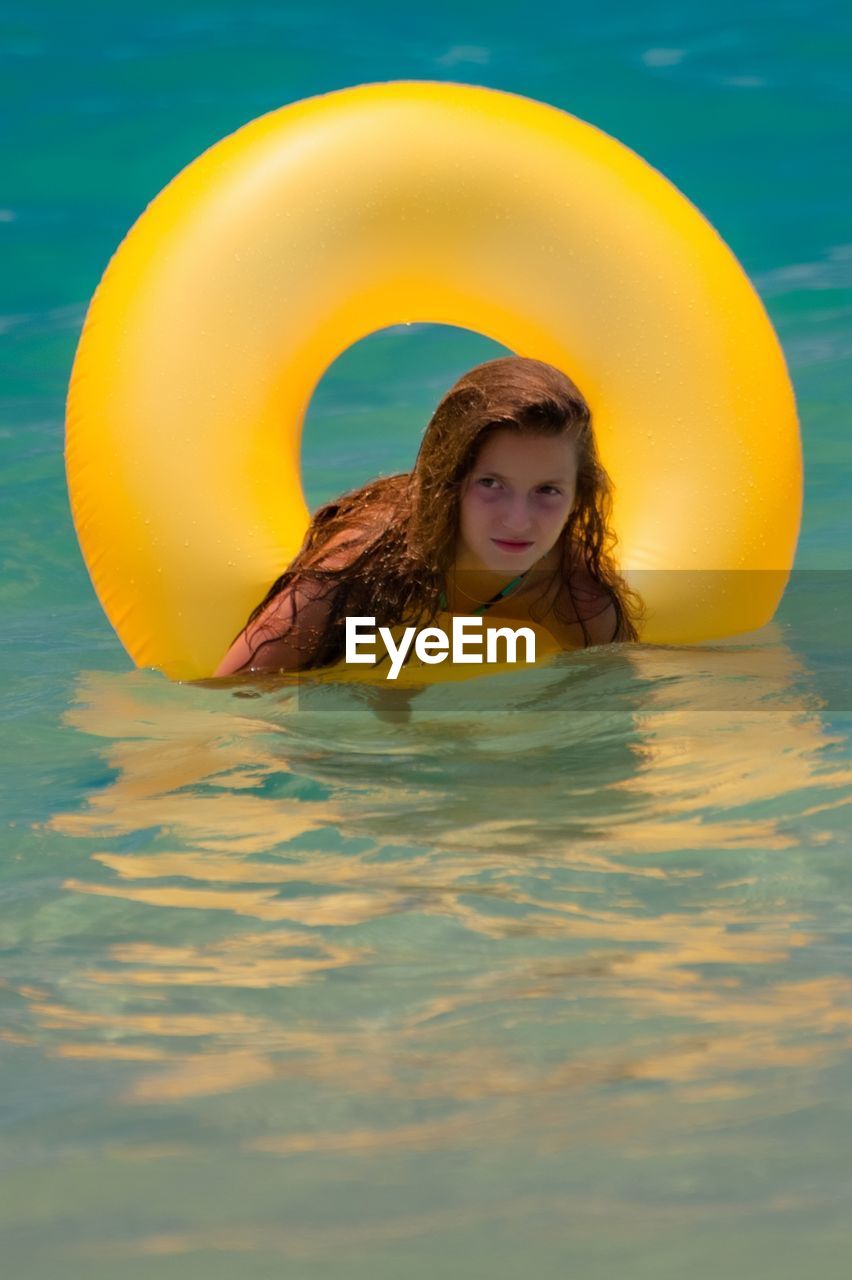 Portrait of teenage girl with inflatable ring floating on sea