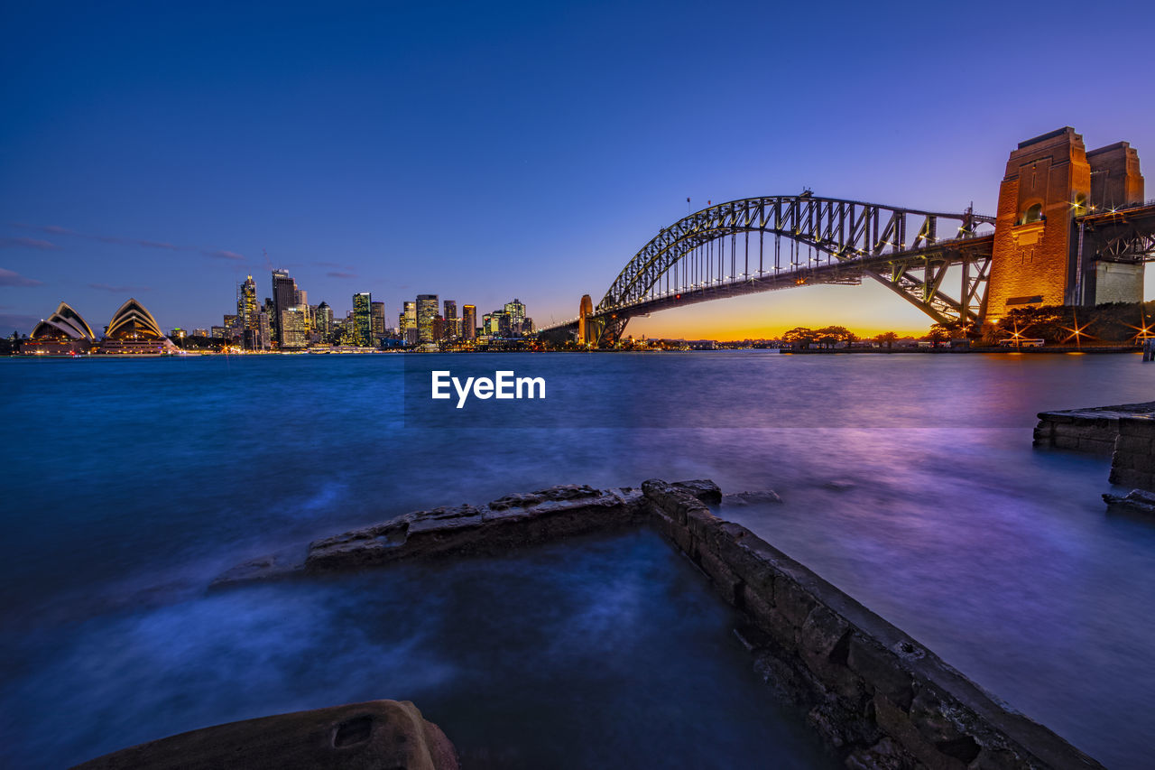 Bridge over sea in city at dusk