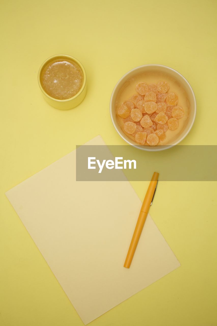 Directly above view of drink and candy by blank paper