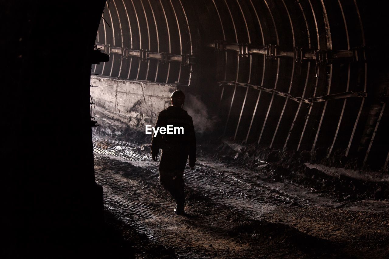 Rear view of silhouette man walking in tunnel