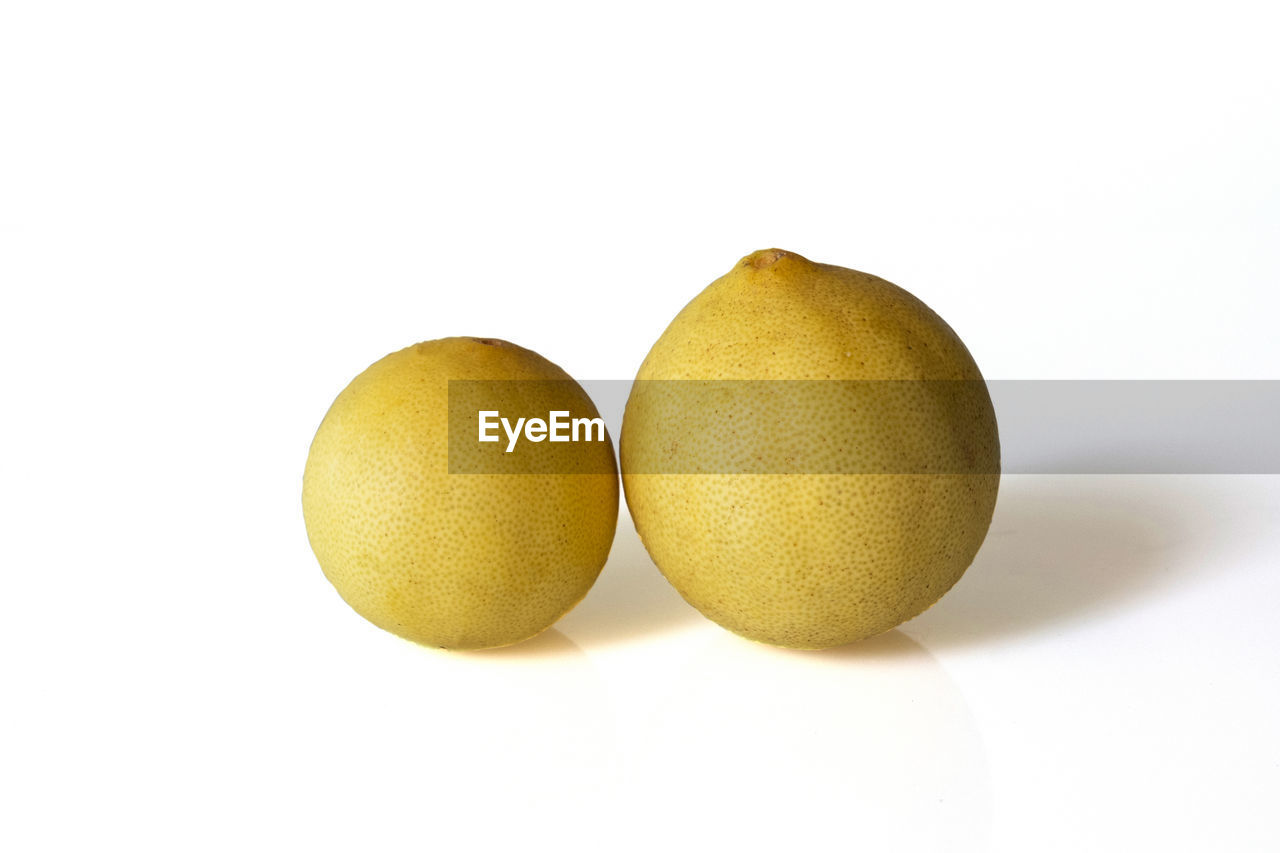 CLOSE-UP OF ORANGES AGAINST WHITE BACKGROUND