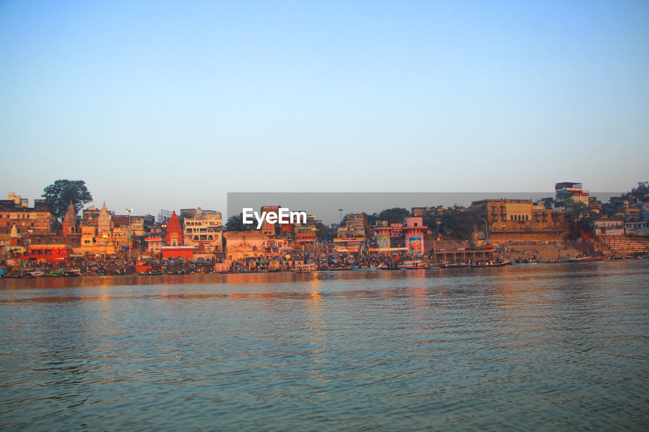 Scenic view of river by buildings against clear sky