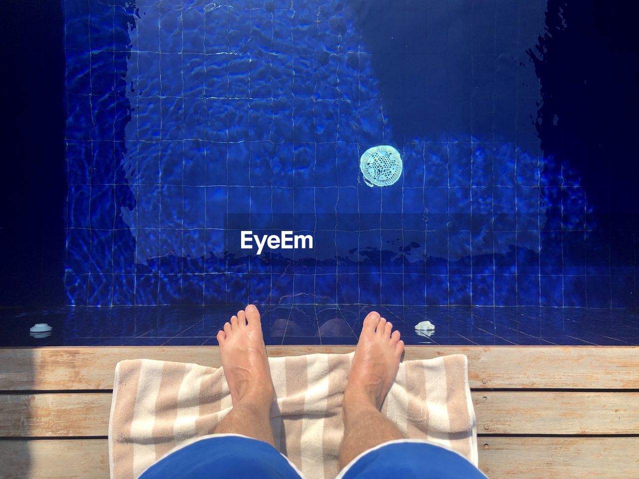 Low section of man standing at poolside