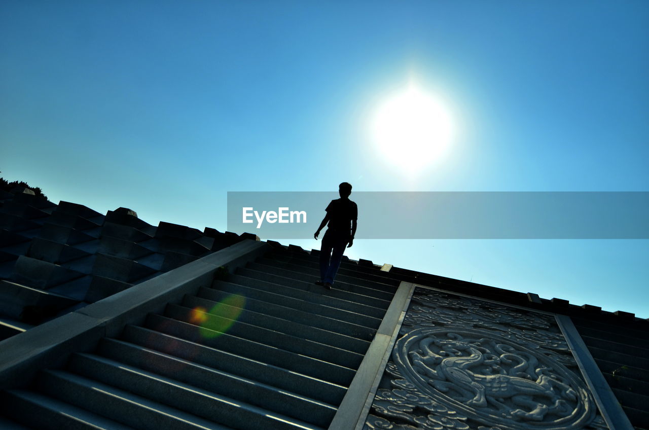 Low angle view of man on steps against sky