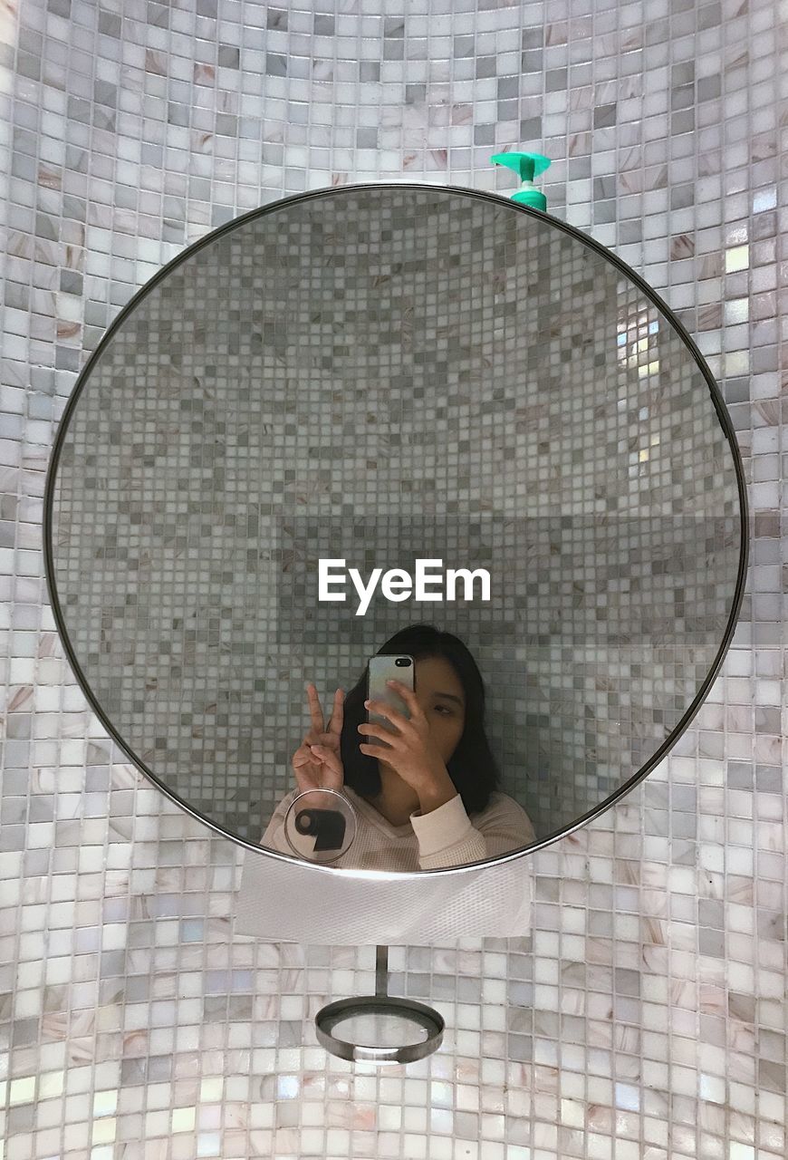 Reflection of woman taking selfie in mirror