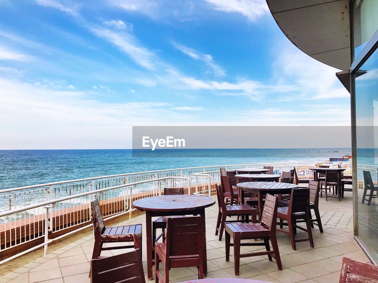 CHAIRS AND TABLES ON BEACH AGAINST SKY