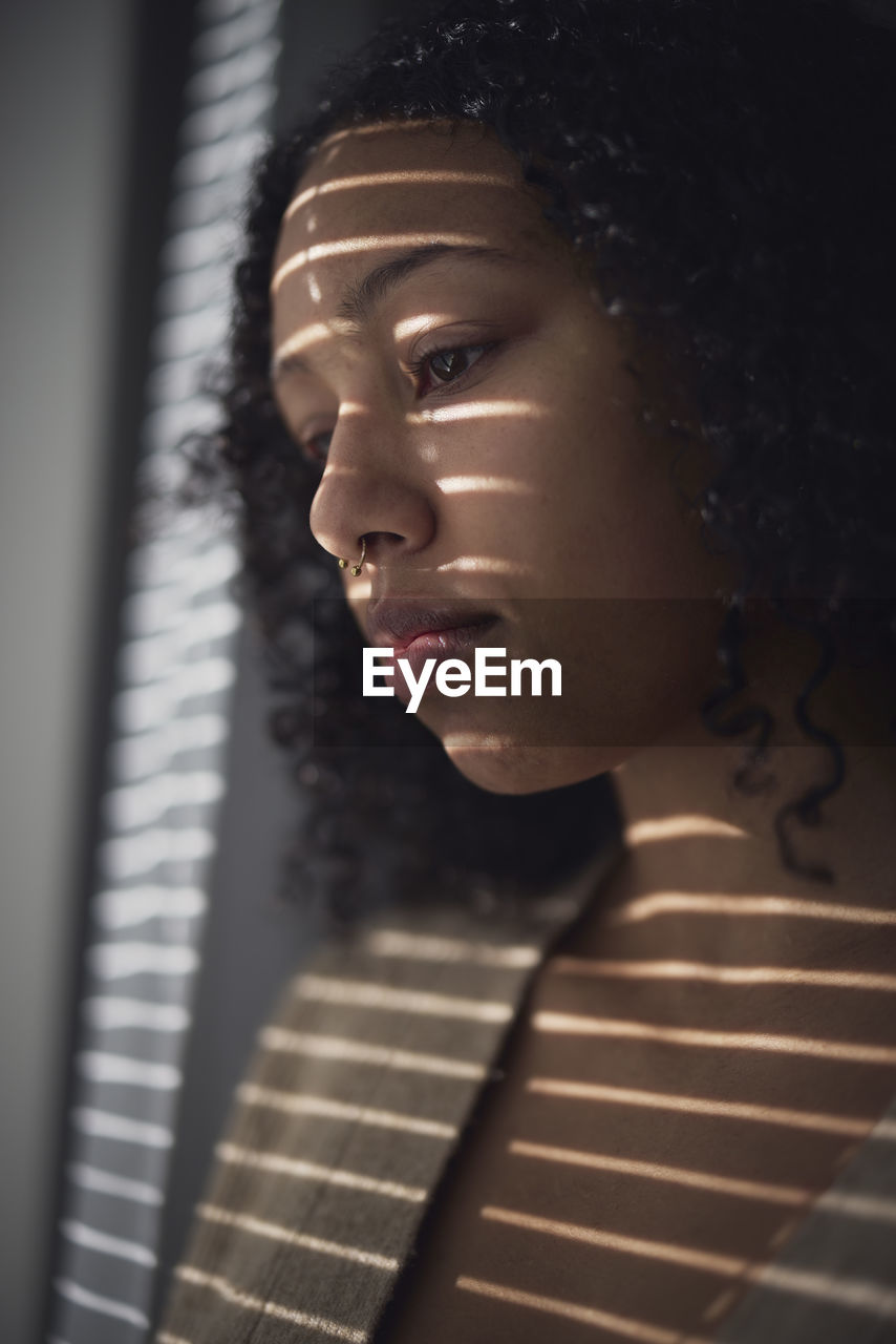 Pensive young woman looking through window