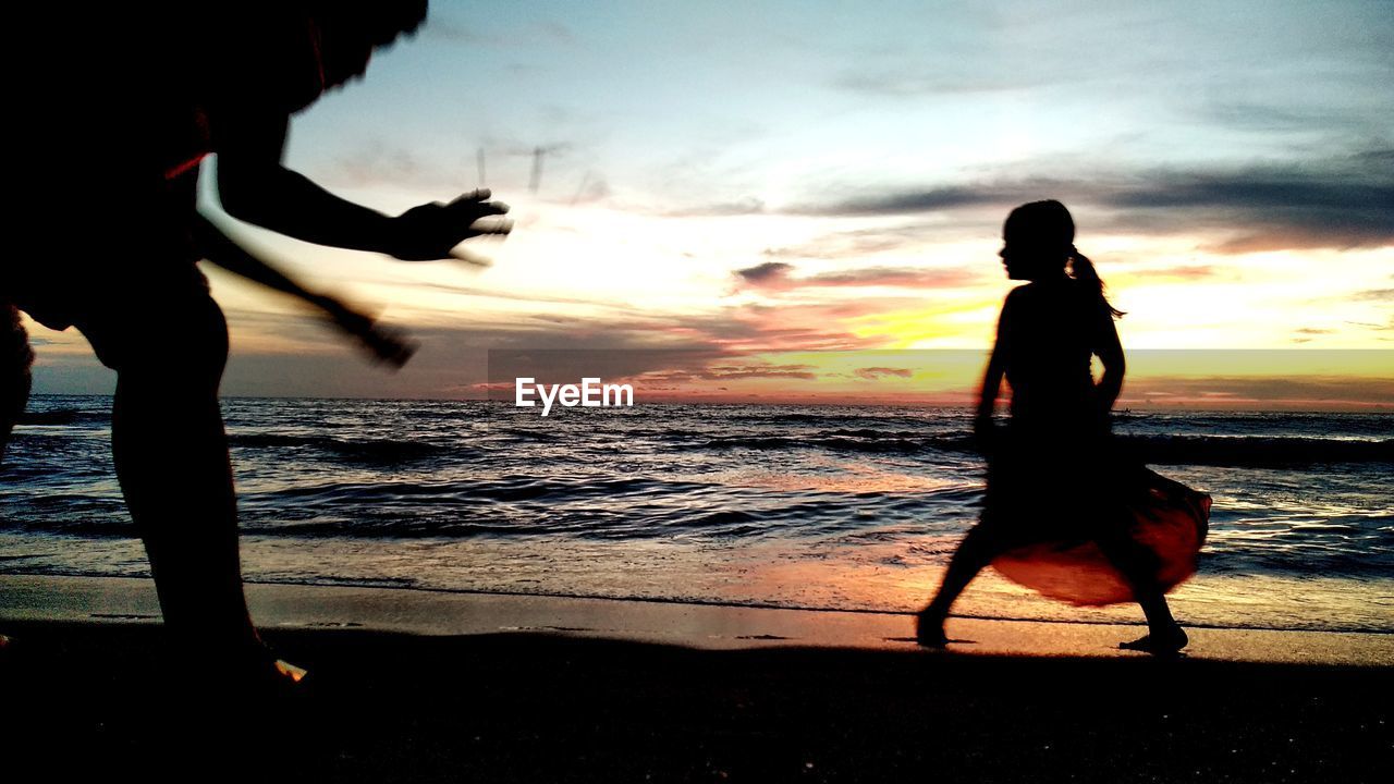 SILHOUETTE WOMAN ON BEACH DURING SUNSET